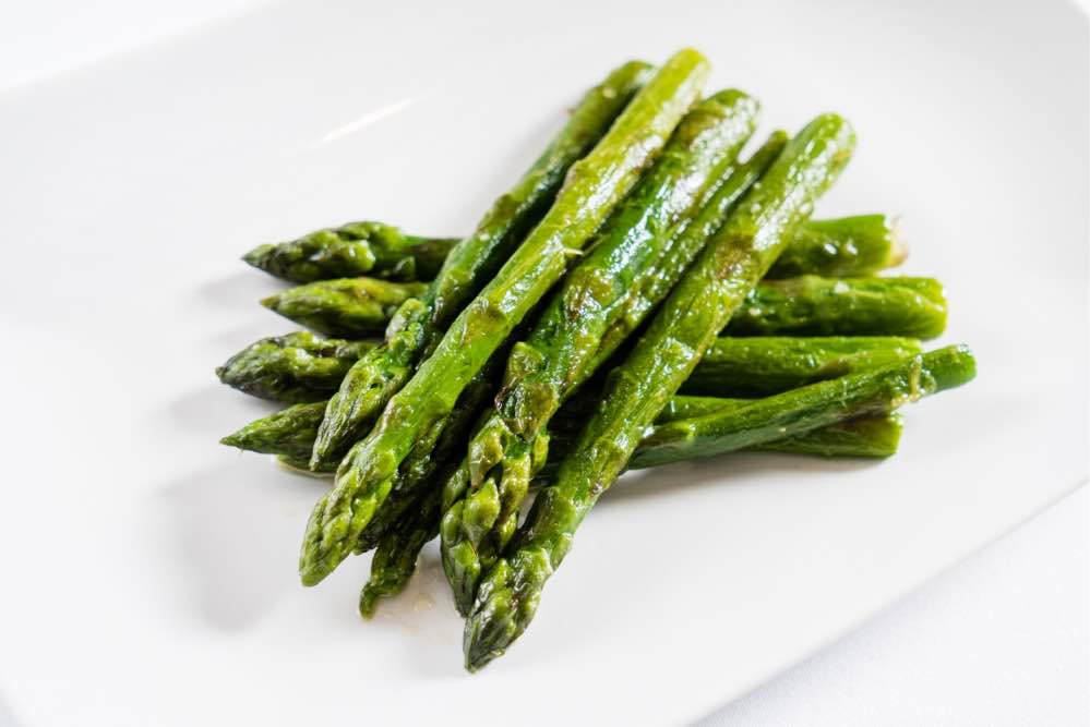 Roasted asparagus spearson a white plate.