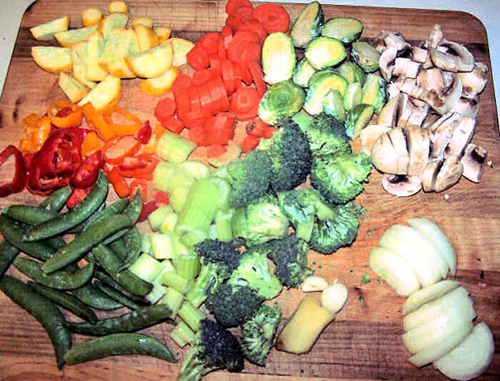 Broccoli, peppers, peas, onions and other vegetables on a cutting board.