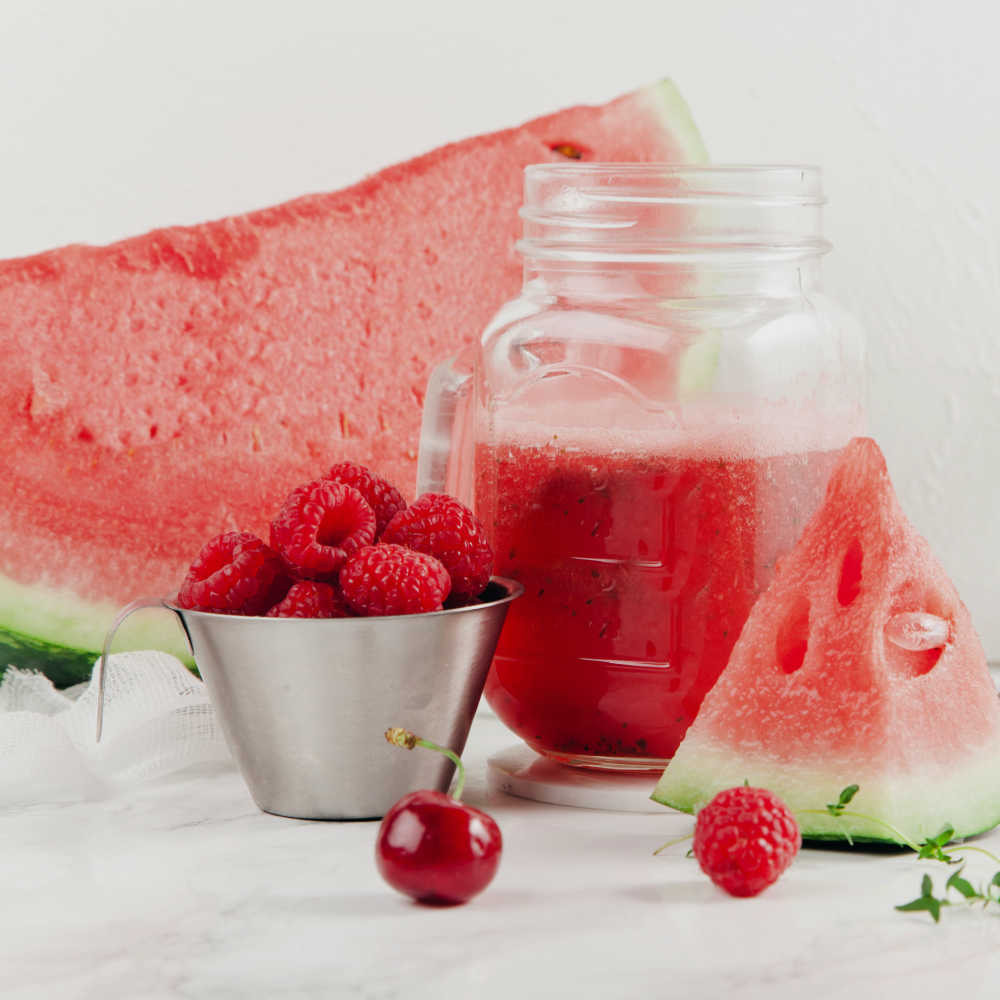 Raspberries and watermelon with Mason jar of juice.