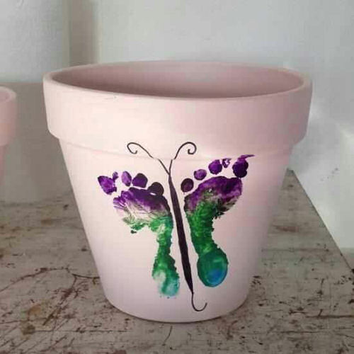 Plant pot decorated with child's feet in a butterfly pattern