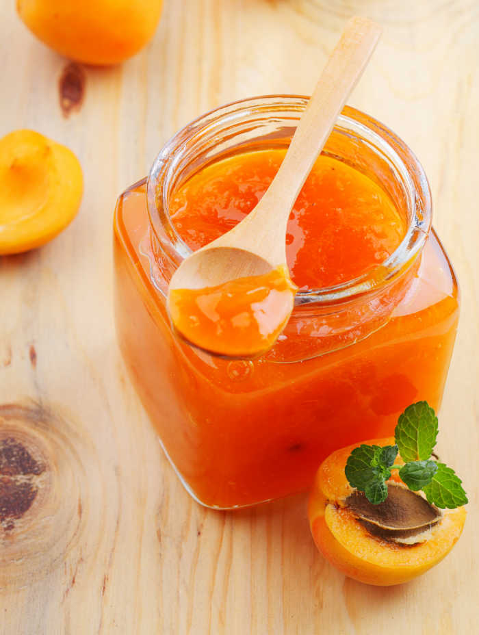 apricots and apricot jam in a jar with a spoon.