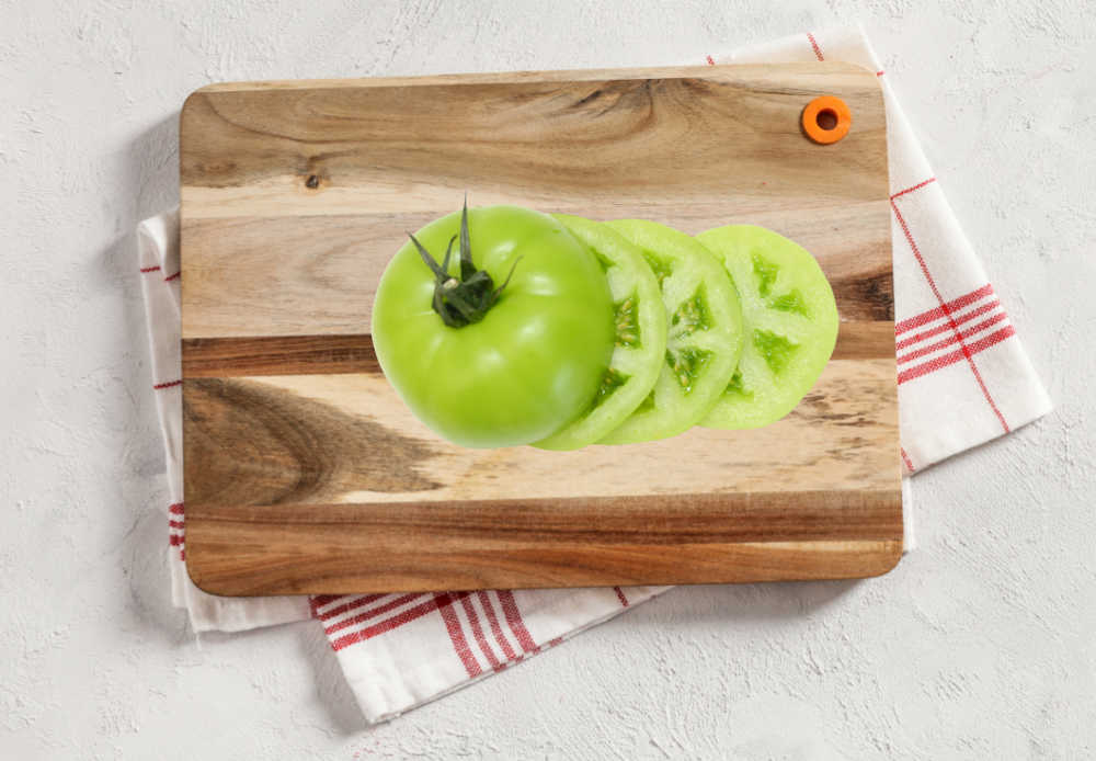 Green tomato slices on a cutting board.