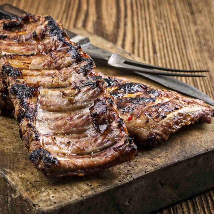 Pork spare ribs on a wooden board with a fork.