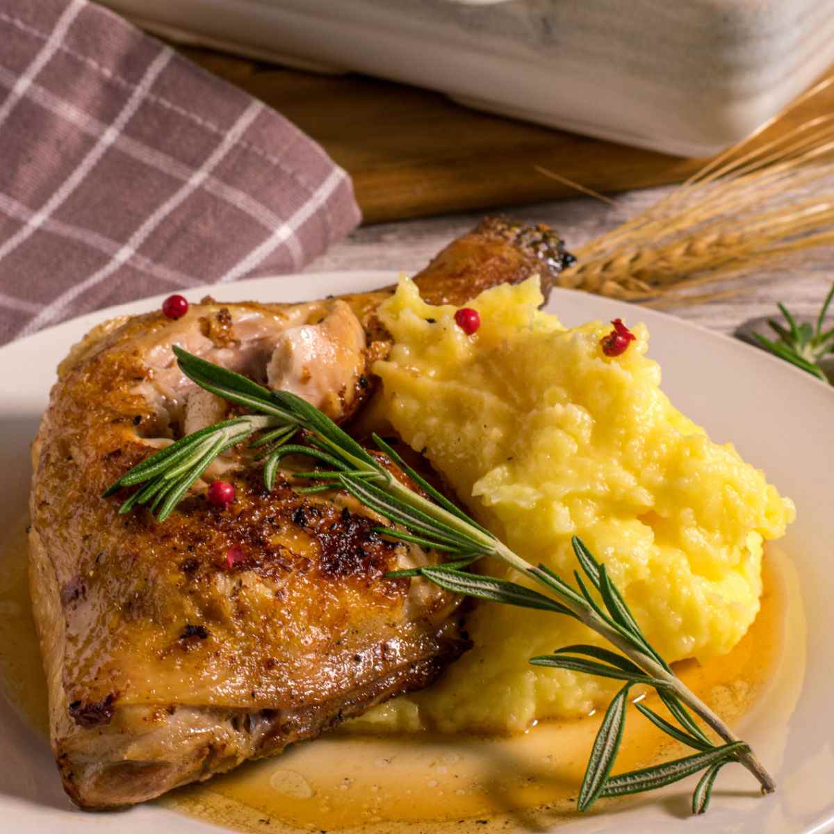 Baked chicken with a sprig of rosemary and smashed potatoes.