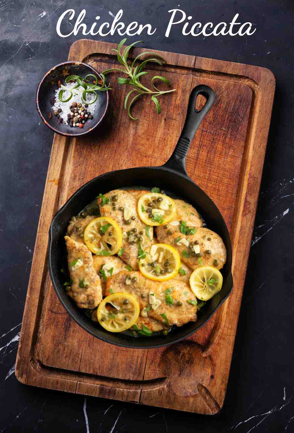 Chicken piccata in a cast iron frying pan on a wooden board.