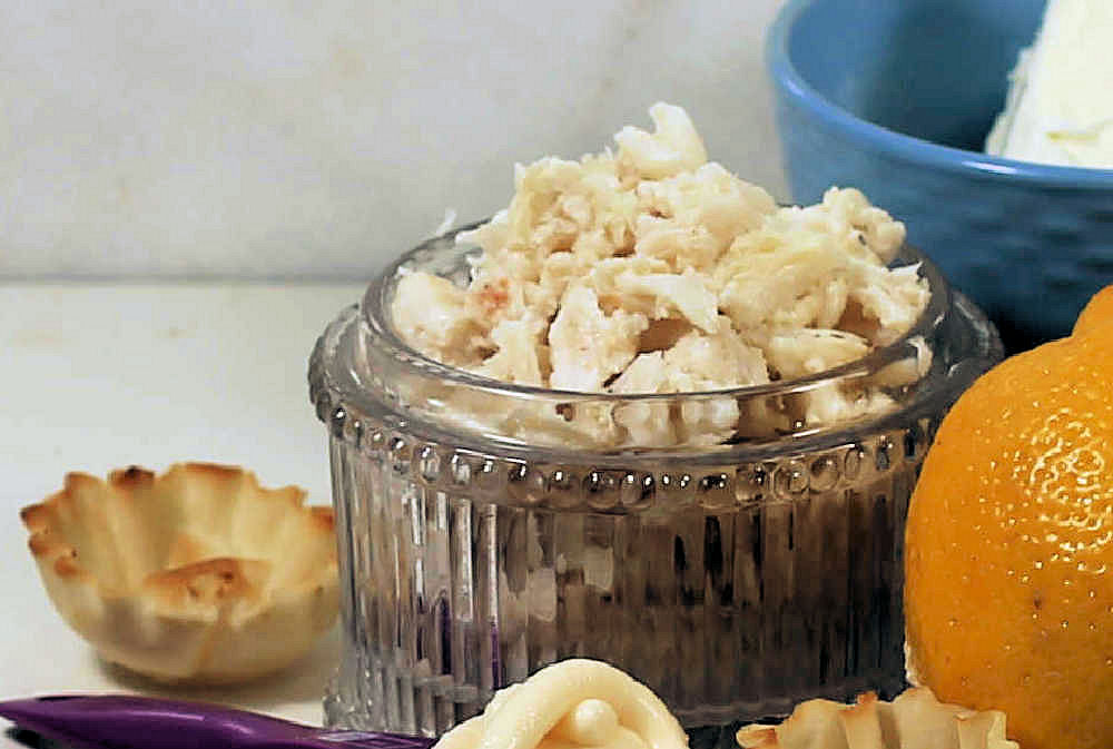 Crab meat in a glass bowl with phyllo cup and lemon.