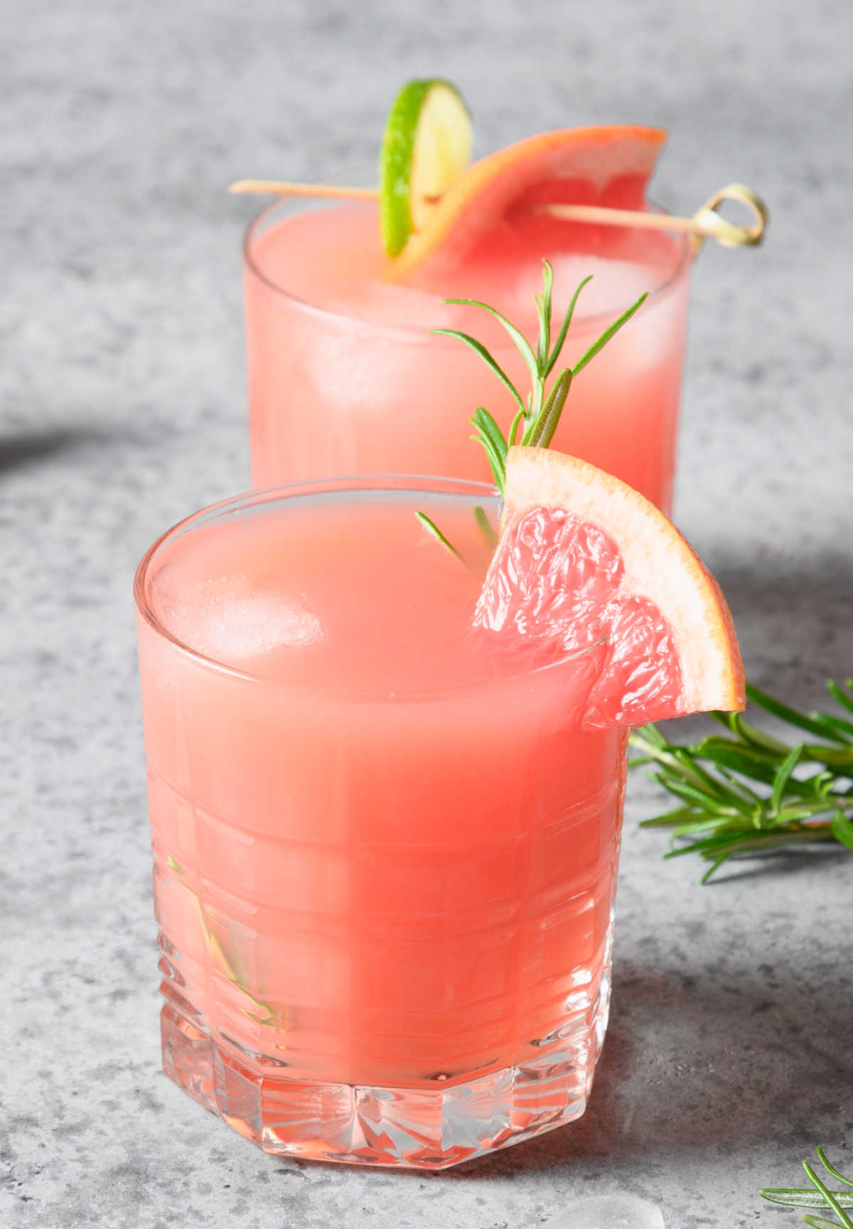 Grapefruit cranberry cocktail Grapefruit drink with lime slice and rosemary
