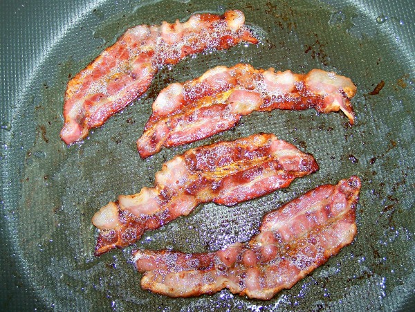 Cooking bacon in a pan for a German potato salad recipe with bacon