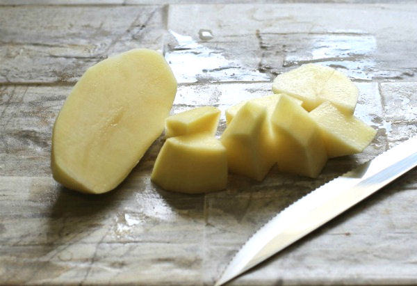 Cutting large chunks of potatoes for an authentic hot German potato salad recipe. Best potatoes for German potato salad are waxy ones like Yukon Gold or Red Bliss.