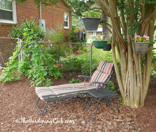Lounging seating area with hanging baskets in the trees and a wind chime.