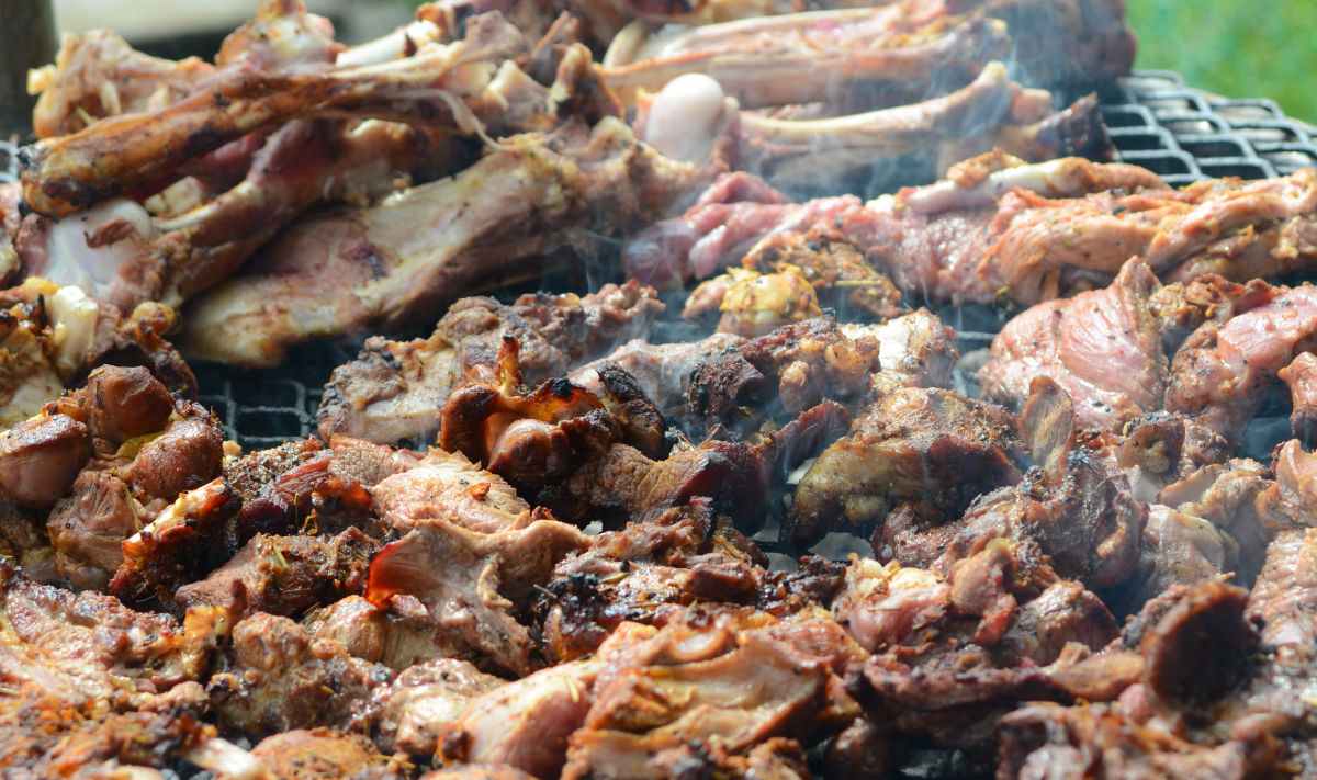 A barbecue grill with too much meat on it.