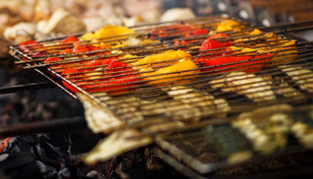 Vegetables in a grill basket over charcoal.