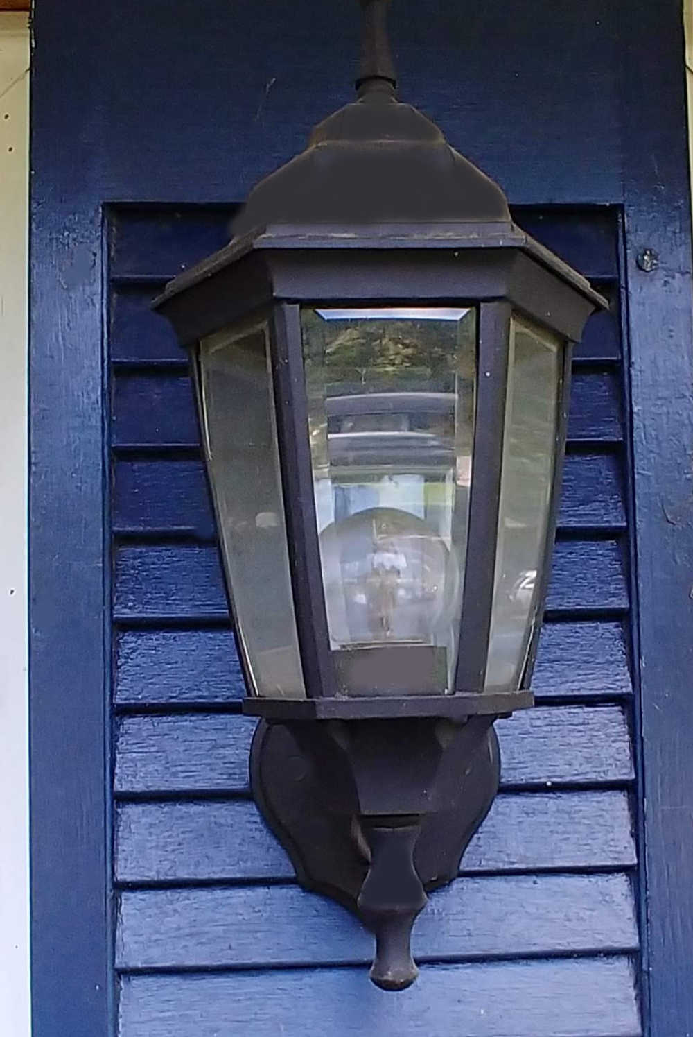 Black lantern on a blue wood shutter.