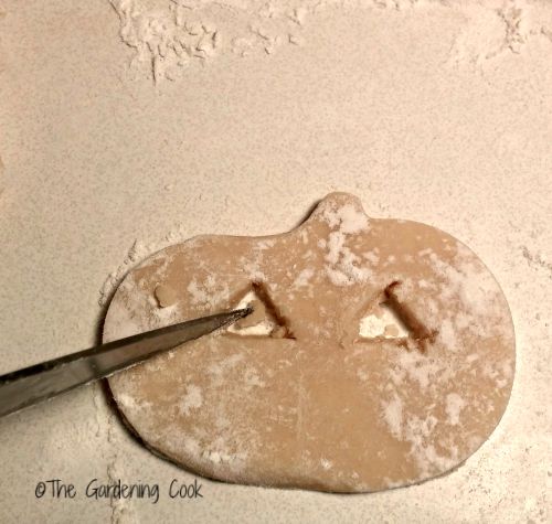 cutting pumpkin faces in dough.