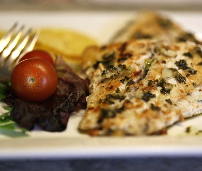 Close up of barramundi with a lemon butter sauce and salad.