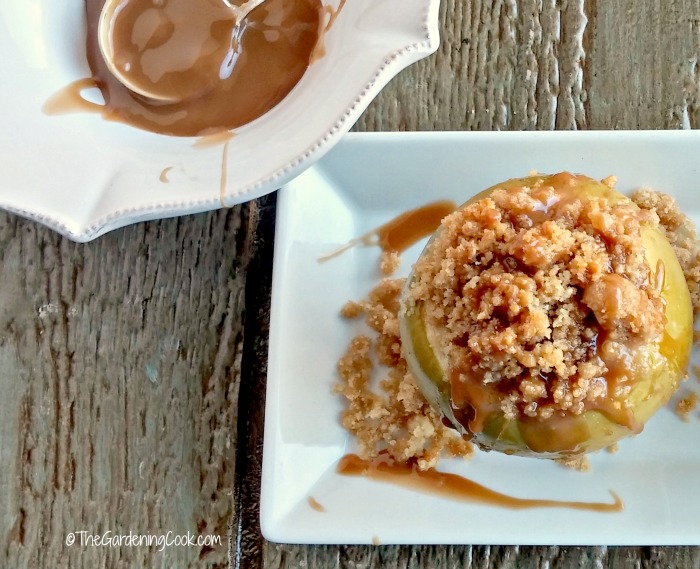 Apple crumble baked apples Apple Crumble baked apples on a white plate with sauce.
