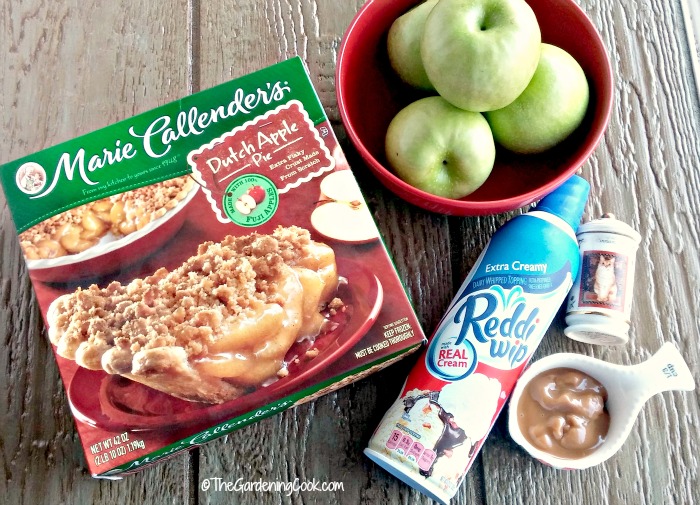 Gather the ingredients to make apple crumble apples Apple pie, apples, cinnamon, caramel topping, and Reddi Whip on a gray board.