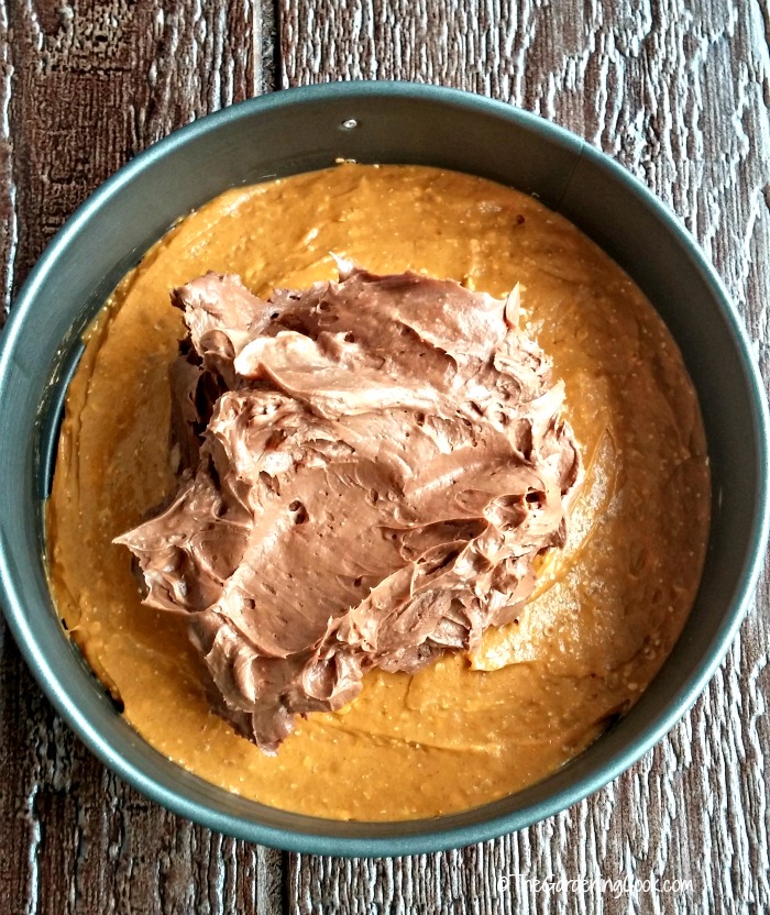 Layers of the pumpkin chocolate cheesecake in a spring form pan.