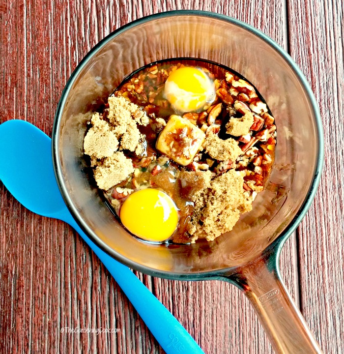 Eggs, brown sugar, butter, and corn syrup in a pan with a blue silicone spoon.