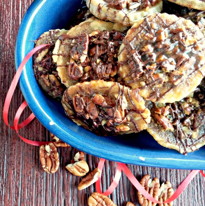 pecan cookies in a blue bowl with red ribbon and loose pecans.