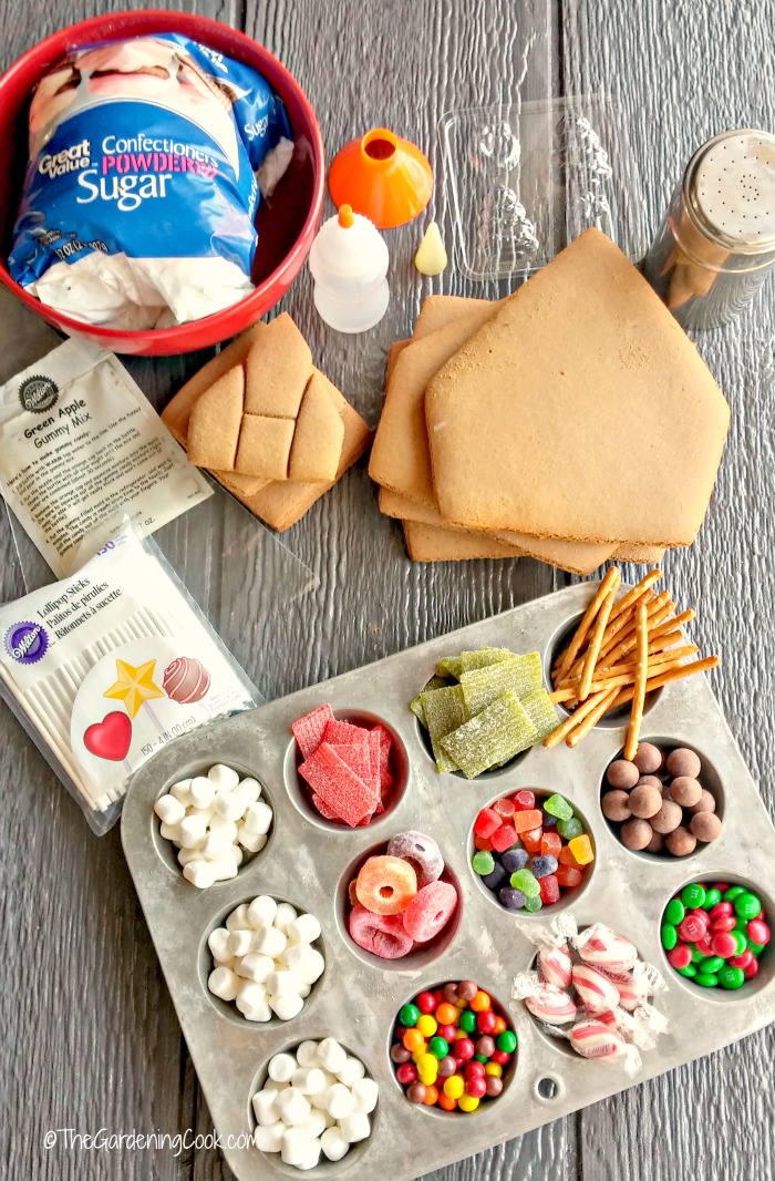 Candy in muffin tins, gingerbread house pieces, sugar and other supplies for making your own gingerbread house.