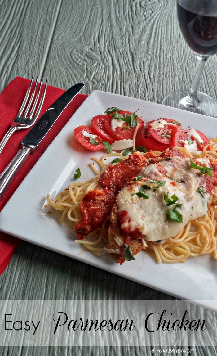 Chicken with spaghetti and tomato salad on a white plate with words Easy Parmesan Chicken.