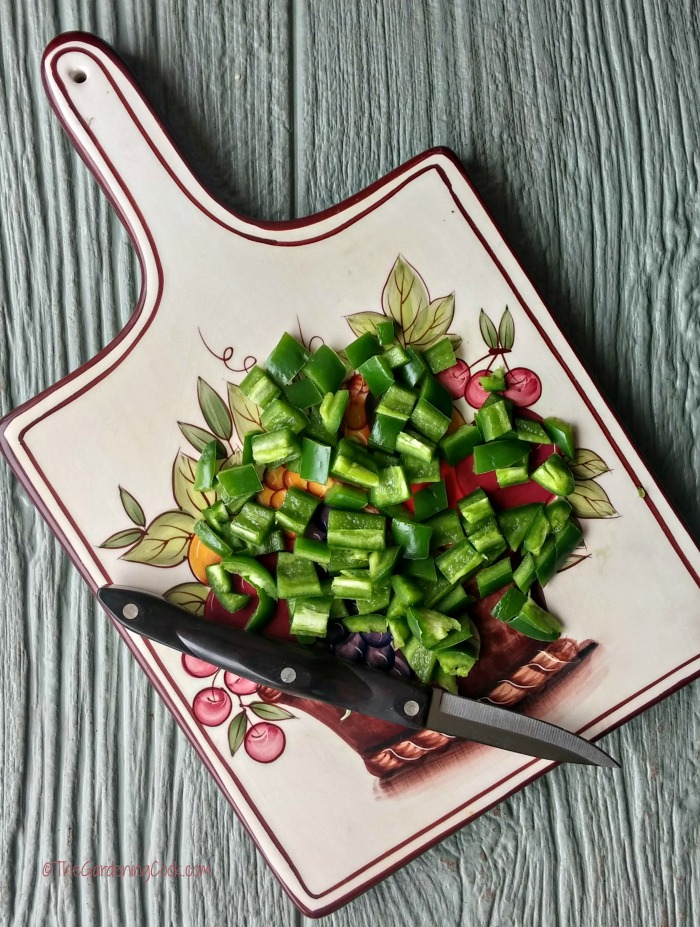 chopped jalapeno peppers on a cutting board with a knife.