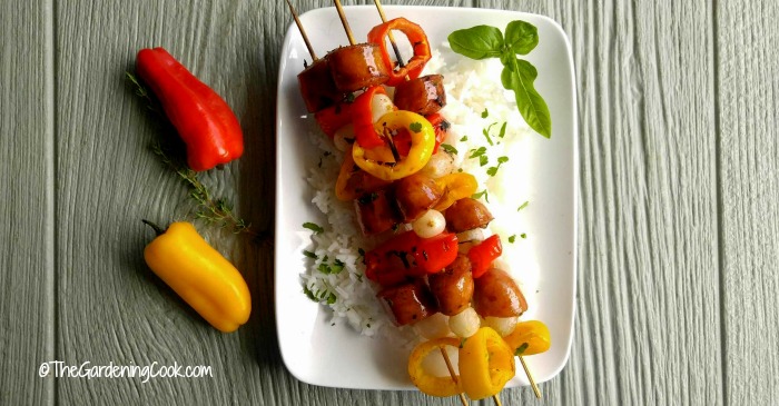 Cajun style Andouille sausage kebabs on a white plate with two chili peppers.