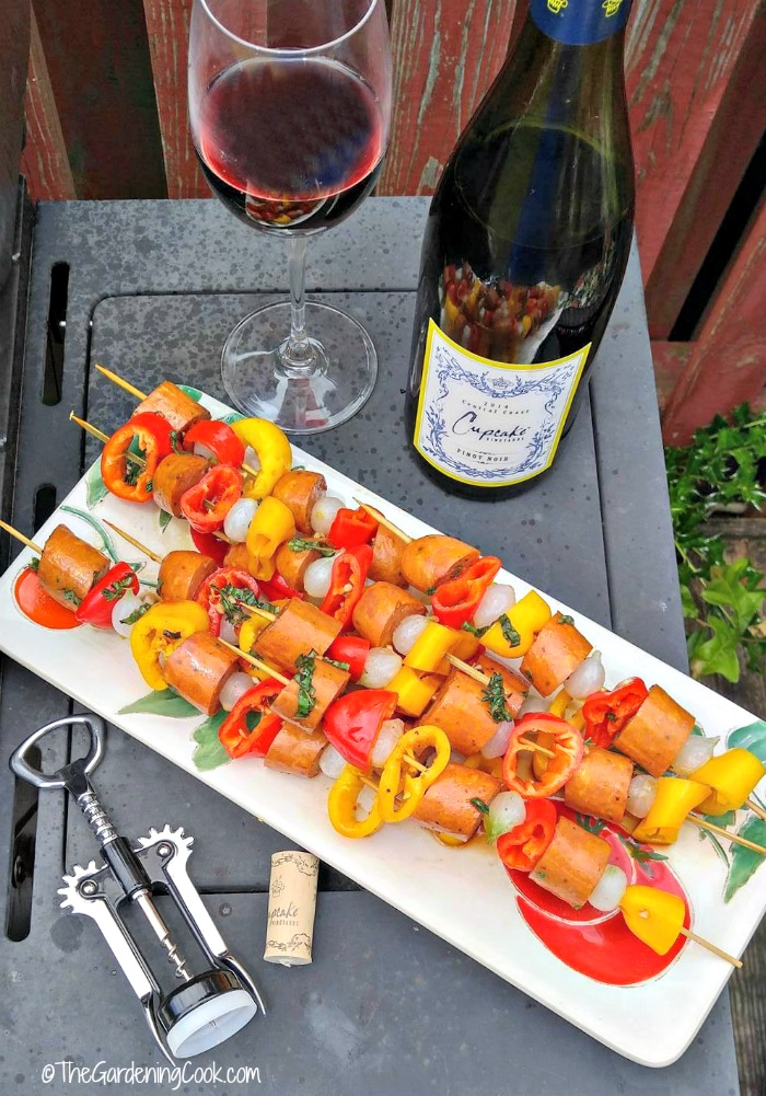 Cajun style Andouille sausage kebabs with wine in a bottle and glass and corkscew.