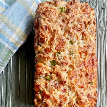 Jalapeno bread on a grey board with a blue plaid napkin.