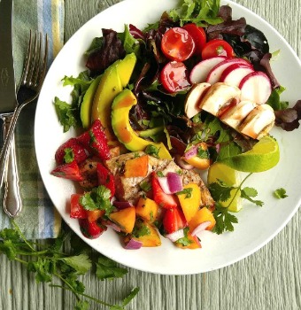 Healthy salad recipe with avocado and dressing on a white plate.