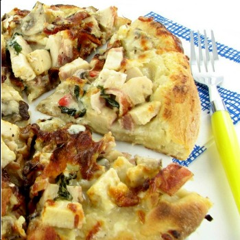 Chicken alfredo pizza recipe with a yellow fork and blue napkin.