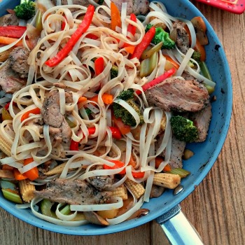 Pork recipe with noodles and vegetables in a frying pan.