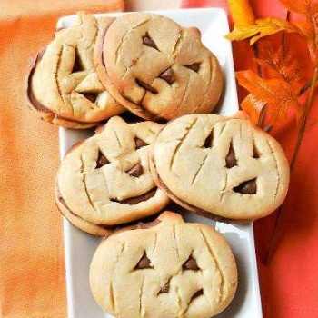 5 pumpkin cookies on a white plate with leaf and orange napkin.