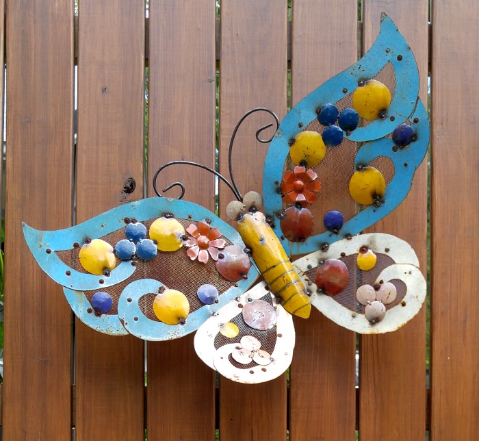 Metal yard art butterfly on a wooden fence