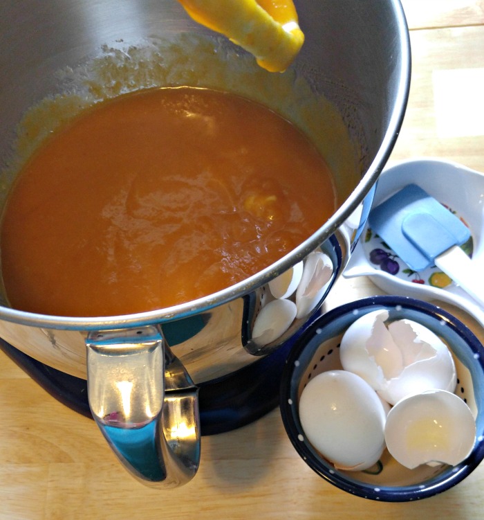 Eggs, oil and butter in a stand mixer with broken eggs in a bowl.