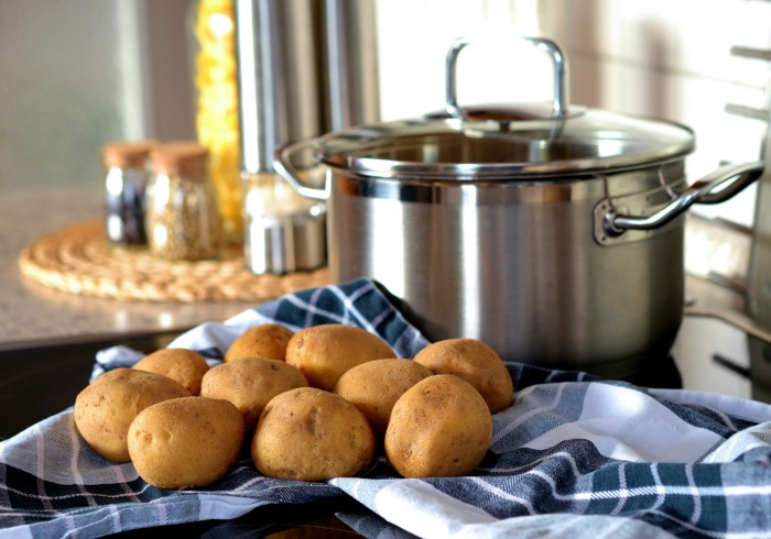 Potatoes and a pot with blue towel and spices.