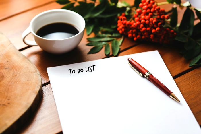 Cut of coffee and flowers with a pen and paper with words to do list.
