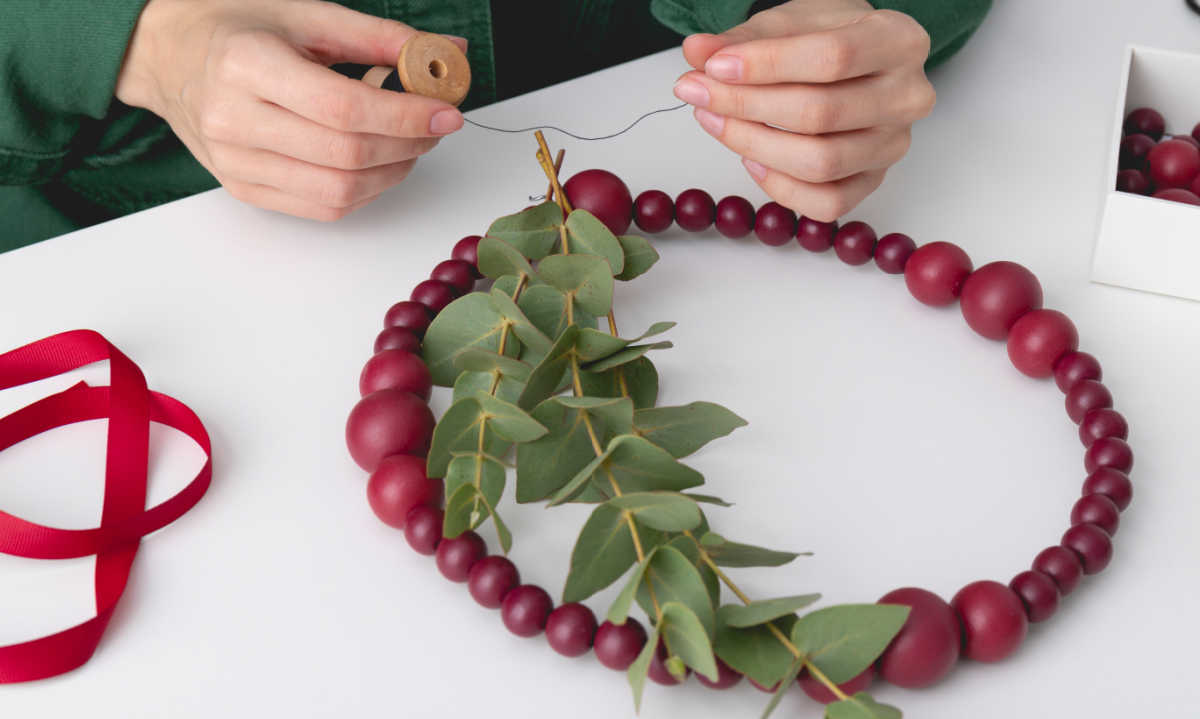 Woman making a wreath out of red balls.