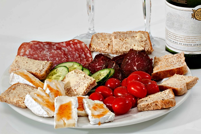 White antipasti platter with sliced meats and vegetables.