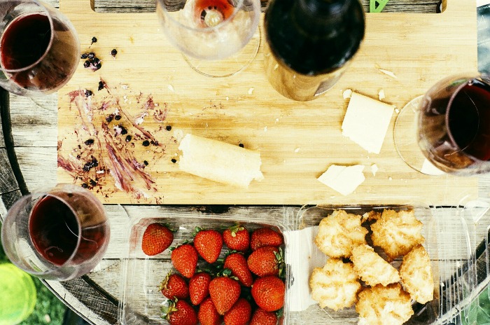 Cutting board with glasses of wine and fruit.