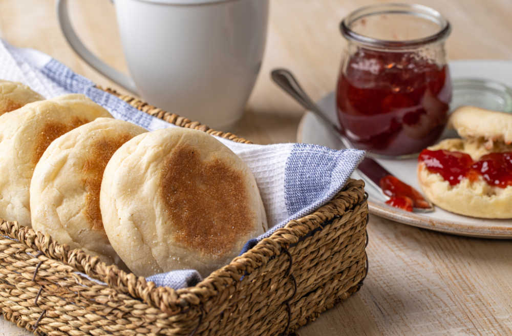 English muffins in a basket with some jam.