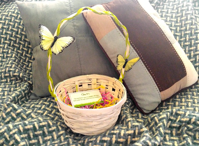 Teenage Easter basket with clue on a blue throw rug near some pillows.