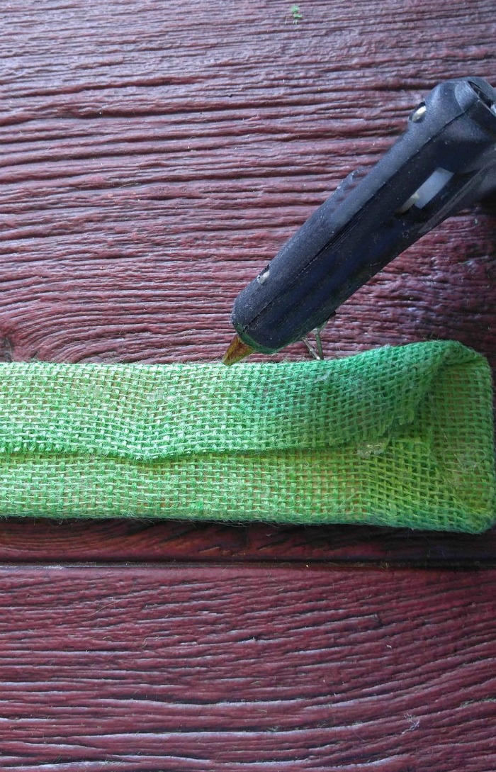Hot glue gun and green burlap material.