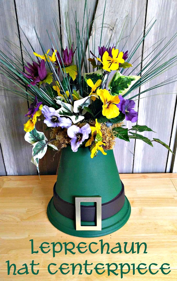 Flowers on top of clay pots painted like a hat and words reading Leprechaun Hat Centerpiece