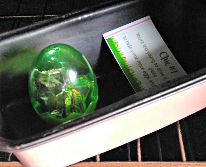 Baking tray in the oven with a clue and green plastic Easter egg.