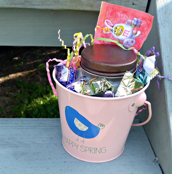 Pink bucket with candle and candy for building an Easter basket with clues.