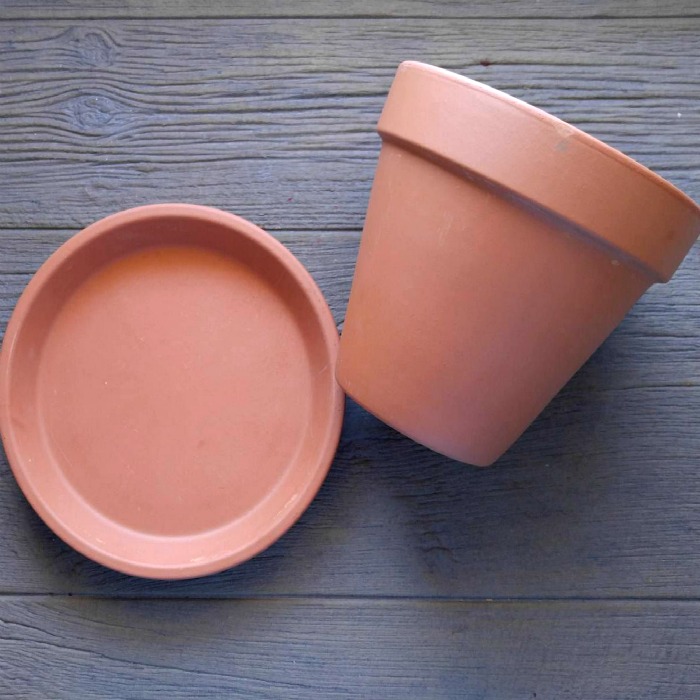 Clay pot and saucer on a wooden board.