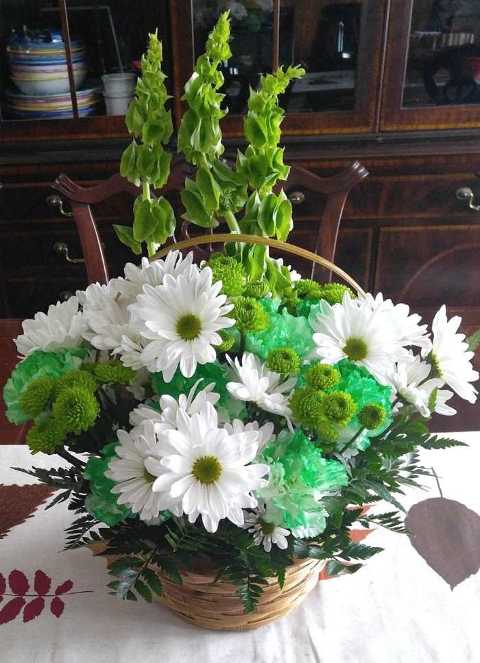 Fresh flowers for St. Patrick's day in a straw basket on a dining room table