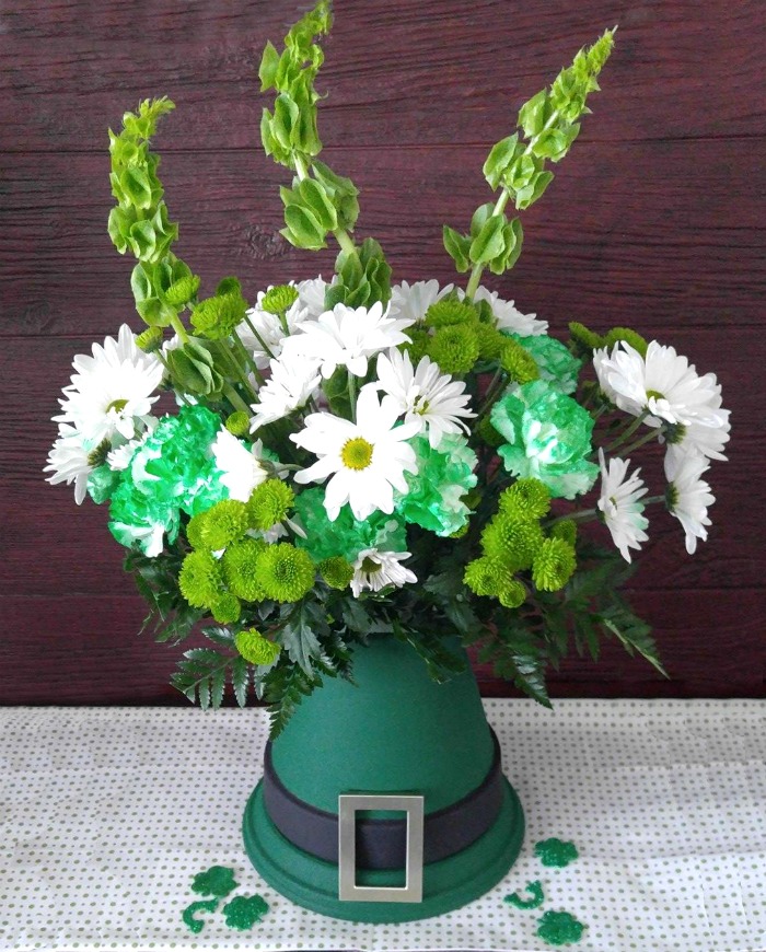 St. Patrick's day table centerpiece decorated with fresh flowers on a leprechaun hat made from clay pots.